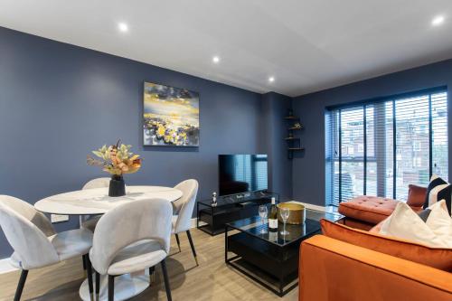 a living room with a table and a couch at Elliot Oliver - Exquisite Two Bedroom Apartment With Garden, Parking & EV Charger in Cheltenham