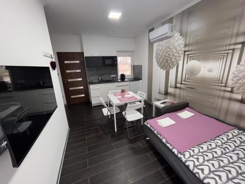 a room with a bed and a table and a kitchen at Sweet Home Apartman in Balatonszárszó