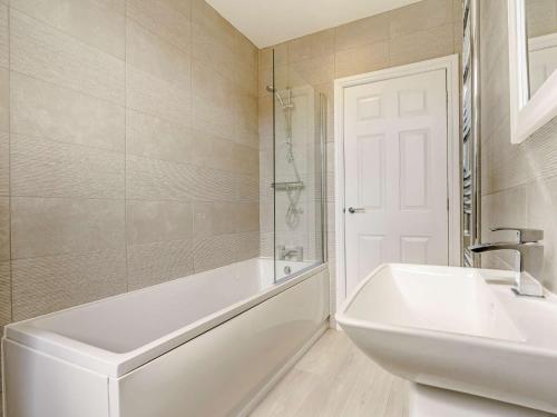 a white bathroom with a tub and a sink at 3 Bed in Wooler 83975 in Wooler