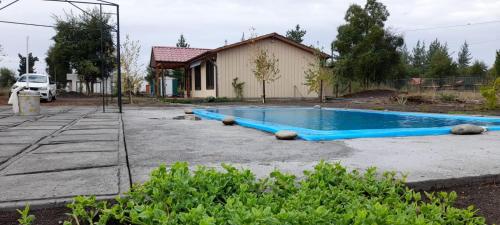 a blue swimming pool in a yard next to a house at Cabaña Individual con piscina en parcela de Quillón in Quillón