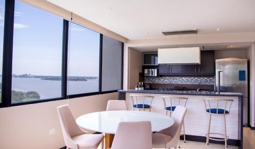 cocina con mesa blanca, sillas y ventanas en Suite 7 Bellini IV, Puerto Santa Ana, Guayaquil, en Guayaquil
