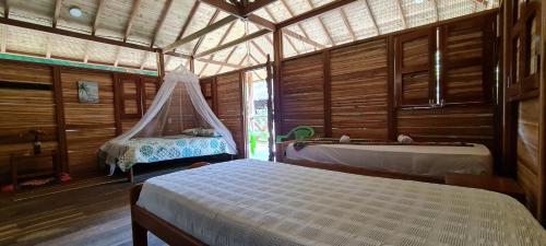 1 dormitorio con 2 camas y bañera. en La Joviseña, en Nuquí