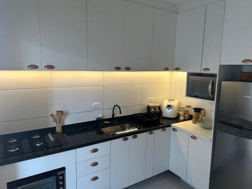 a white kitchen with a sink and a refrigerator at CASA DE PRAIA OLONAN BEACH in Itanhaém