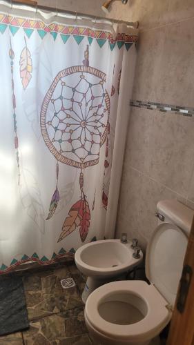 a bathroom with a toilet and a shower curtain at Cabaña Los Abuelos in Coronel Moldes