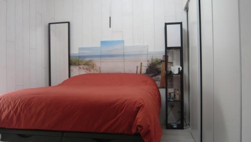 um quarto com uma cama com um cobertor vermelho em MAISONNETTE AU BORD DE L ETANG em Leucate