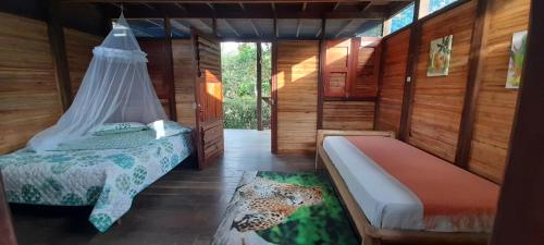 a bedroom with two beds in a room with wooden walls at La Joviseña in Nuquí