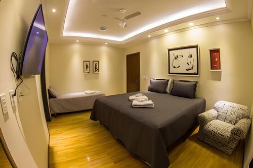 a bedroom with a bed and a chair and a tv at Casa ampla e confortável próxima ao Santuário in Aparecida