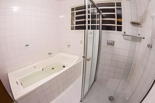 a white bathroom with a tub and a shower at Casa ampla e confortável próxima ao Santuário in Aparecida