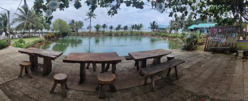 a group of tables and stools in front of a pond at Chattong resort in Trat
