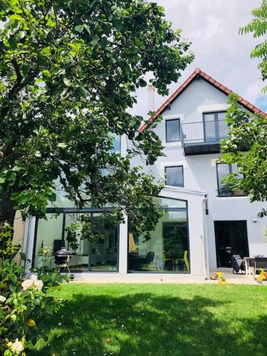 une grande maison blanche avec une pelouse devant dans l'établissement Maison climatisée aux portes de Paris, à Suresnes