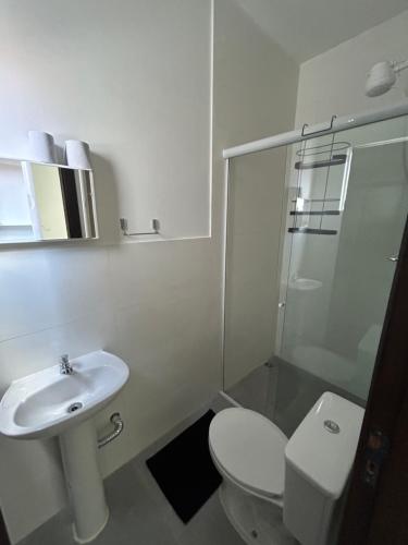 a white bathroom with a toilet and a sink at Pousada Tamatoa Suítes in Florianópolis