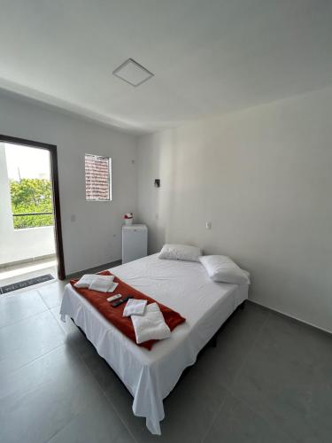 a white bedroom with a large bed with towels on it at Pousada Tamatoa Suítes in Florianópolis
