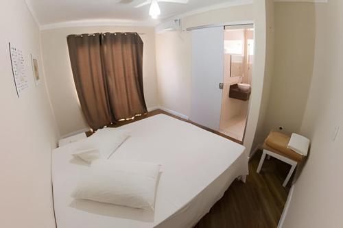 een kleine kamer met een wit bed en een raam bij Casa Aconchegante próxima ao Santuário in Aparecida