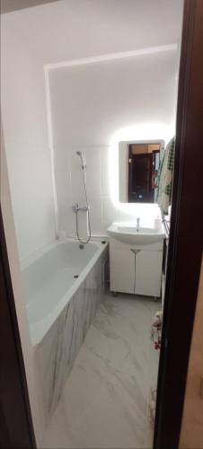 Baño blanco con bañera y lavamanos en 1-комнатная квартира мкр. Аэропорт, en Kostanái