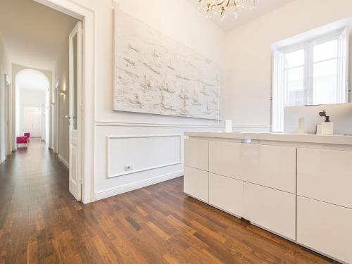 a kitchen with white cabinets and wood floors and a chandelier at PLEY Cagliari Boutique Rooms in Cagliari