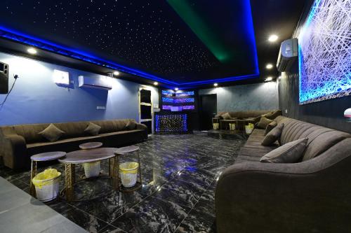 ein Wohnzimmer mit Sofas und einer Bühne mit blauen Lichtern in der Unterkunft شاليهات يارا القيروان in Riad