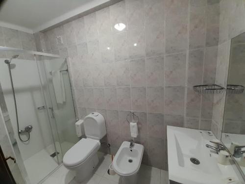 a bathroom with a toilet and a shower and a sink at Hotel Dom Joao IV in Guimarães