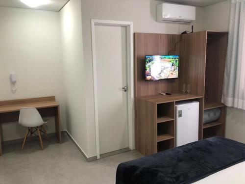 um quarto com uma cama e uma secretária com uma televisão em Hotel Penedo Inn em Penedo