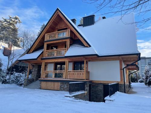 una casa di tronchi con neve sul tetto di Owce Dwie a Zakopane