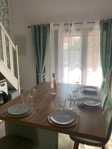 une table en bois avec des assiettes et des verres à vin dessus dans l'établissement La Villa du Port - Cosy - Clim - proche plage - 4 personnes, à Canet