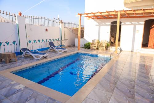 een zwembad met stoelen en een huis bij Calm moon nights hostel in Al Aqālitah