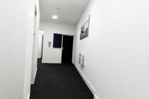 a hallway with white walls and black carpet at Gold Reserve Retreat in Brierley Hill