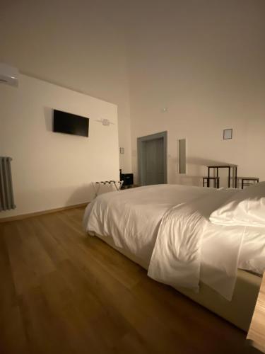 a bedroom with a white bed and a wooden floor at Le Stanze Di Ambra in Trani