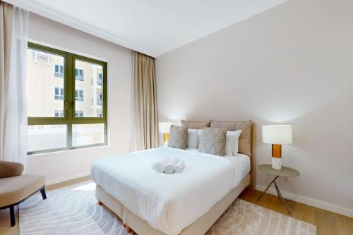 a white bedroom with a bed and a window at La Voile Building 1 - Locations in Dubai