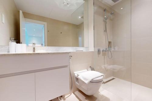 a white bathroom with a toilet and a shower at La Voile Building 1 - Locations in Dubai