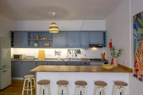 a kitchen with blue cabinets and bar stools at Apartamento Aires - Trafaria in Trafaria