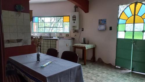 Habitación con mesa y cocina con vidrieras. en Residencia zona sierras chicas (casa) El talar en Mendiolaza