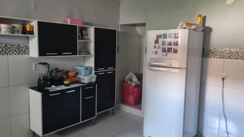a kitchen with a white refrigerator and black cabinets at Caucaia Cit in Caucaia