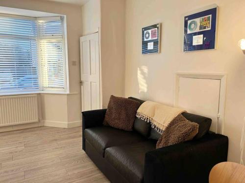 a living room with a black couch and a window at Cool 2 Bed Hornchurch House, Arcade Games, Free Parking in Hornchurch
