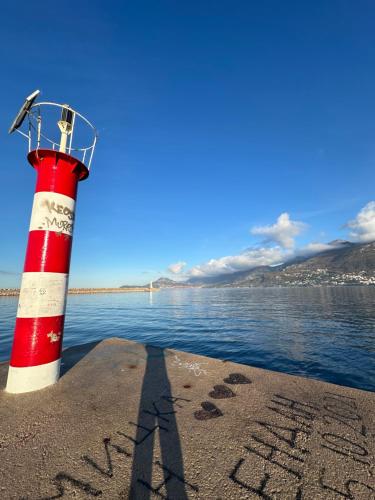 um farol vermelho e branco na costa de uma massa de água em Urban Oasis em Šušanj