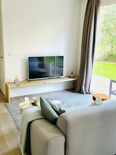 a living room with a couch and a flat screen tv at Chalet goudmeer LUXURY AIRCO WIFI 3 bedrooms 2 bathrooms in Oosterwolde