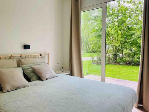 um quarto com uma cama grande e uma janela grande em Chalet goudmeer LUXURY AIRCO WIFI 3 bedrooms 2 bathrooms em Oosterwolde