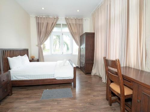 Schlafzimmer mit einem Bett, einem Schreibtisch und einem Fenster in der Unterkunft Villa sealinks Mũi né in Ấp Phú Tịnh (2)