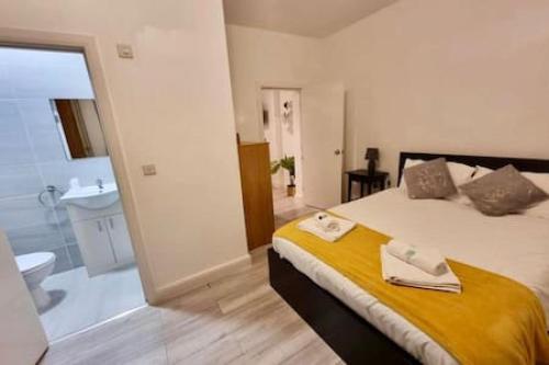 a bedroom with a large bed and a bathroom at Stylish En-Suit near Central in Edgware