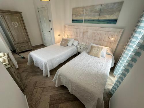 1 Schlafzimmer mit 2 Betten und weißer Bettwäsche in der Unterkunft Puerta la Mar in Tarifa