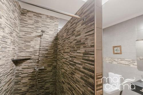 a bathroom with a shower with a stone wall at Villa Ra by MarCalma in Les tres Cales