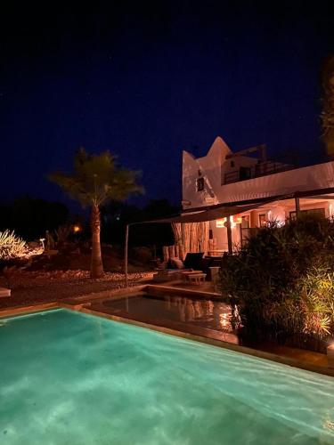 a swimming pool in front of a house at night at Les jardins de Silona, piscine chauffée in Essaouira