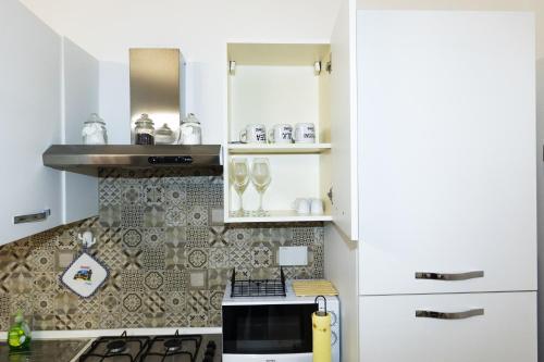 une cuisine avec des armoires blanches et un four à plaques de cuisson dans l'établissement Assisi Suite Relax, Bilocale nel centro storico, à Assise