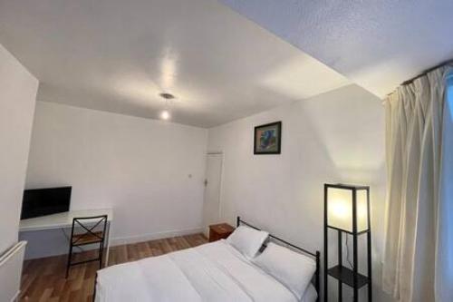 a white bedroom with a bed and a desk at Twin Tranquility- Room in Leyton in London