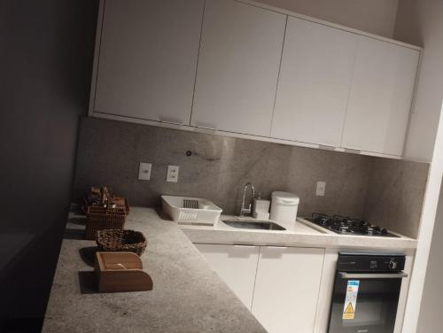 a kitchen with white cabinets and a sink at Apartamento Condomínio Villaggio di Mare - Barra Grande, Maraú - BA in Marau