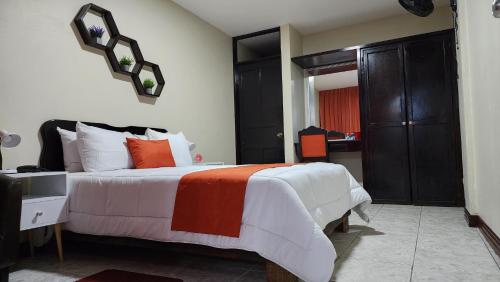 a bedroom with a bed with orange and white pillows at Hotel América Heredia in Heredia