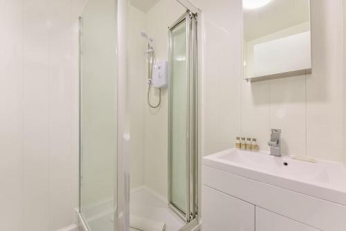 baño blanco con ducha y lavamanos en 2 Bed Piccadilly Apartment- 1, en Londres