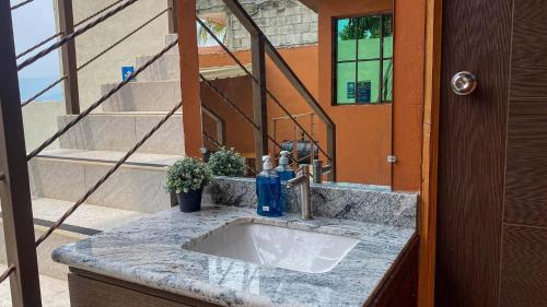 a bathroom counter with a sink and a mirror at Quinta Sunrise, Lago de Coatepeque in El Congo