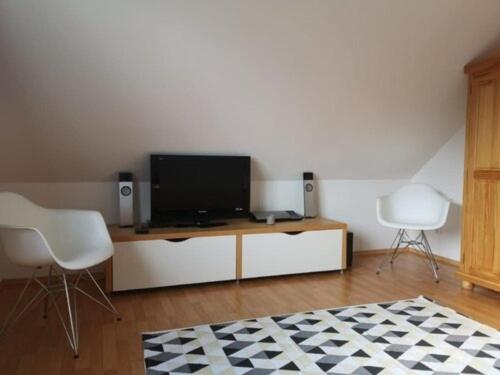 uma sala de estar com televisão e duas cadeiras em Ferienhaus Lille Strandhus em Holnishof