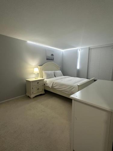 a white bedroom with a bed and a night stand at Osaru Abel Omoruyi in Mississauga