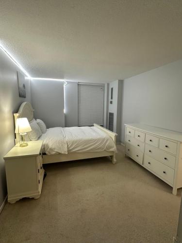 a white bedroom with a bed and a dresser at Osaru Abel Omoruyi in Mississauga